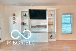 interior space featuring built in shelves, baseboards, and wood finished floors