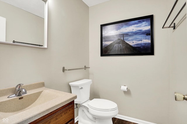 half bath featuring wood finished floors, vanity, toilet, and baseboards