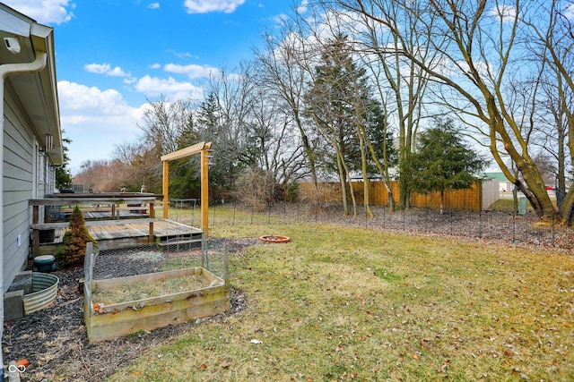 view of yard featuring a garden, fence, and a wooden deck