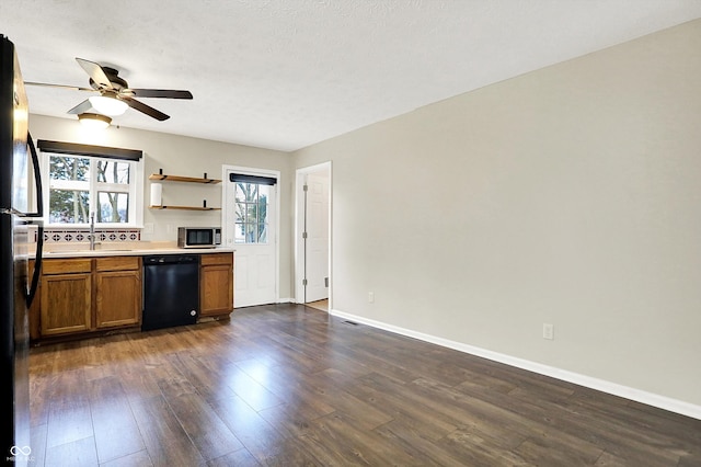 kitchen featuring a sink, light countertops, black appliances, brown cabinetry, and dark wood finished floors