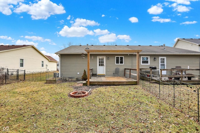 back of property with a yard, an outdoor fire pit, a fenced backyard, and a wooden deck