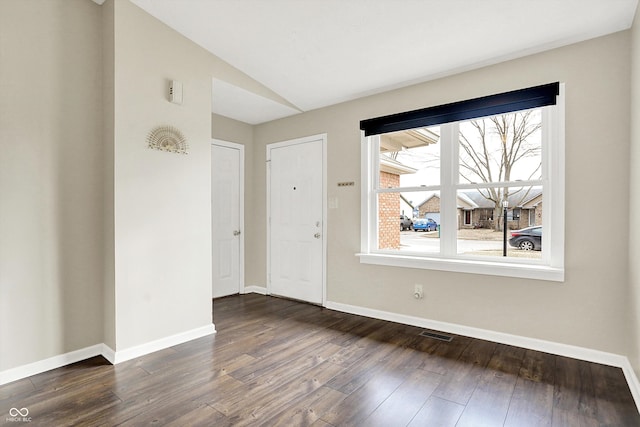 spare room featuring lofted ceiling, dark wood-style flooring, visible vents, and baseboards