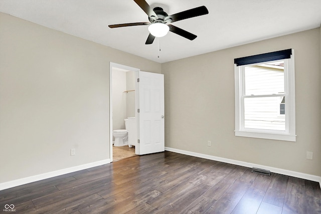 unfurnished room featuring dark wood-style floors, a ceiling fan, visible vents, and baseboards