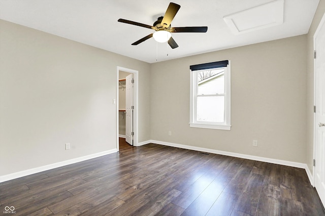 unfurnished room with attic access, dark wood-style flooring, ceiling fan, and baseboards