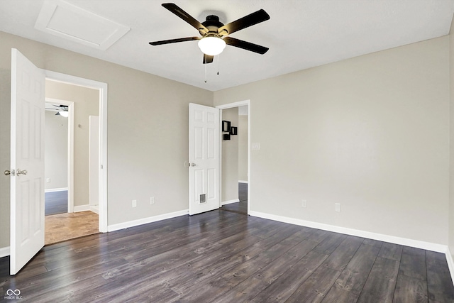 unfurnished bedroom featuring dark wood-style floors, attic access, baseboards, and ceiling fan