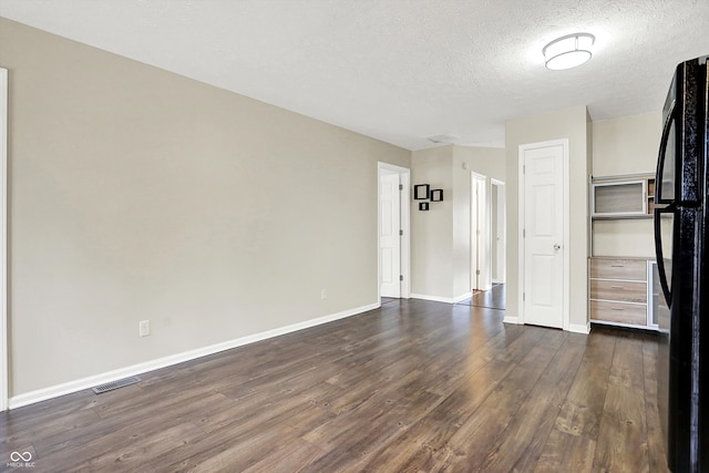 spare room featuring dark wood-style floors, a textured ceiling, visible vents, and baseboards