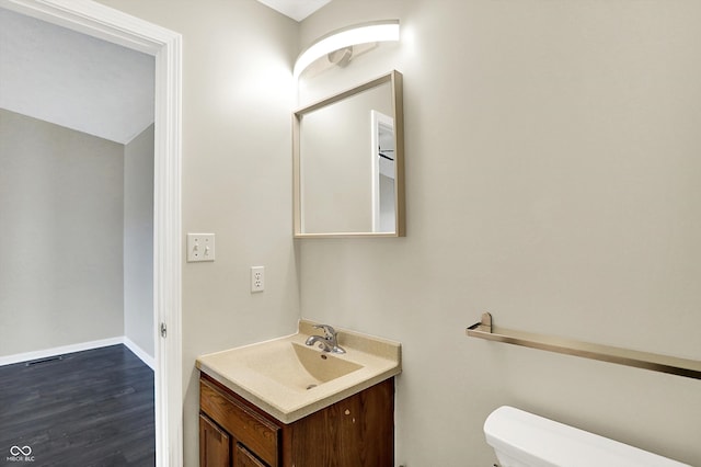 bathroom with baseboards, vanity, toilet, and wood finished floors