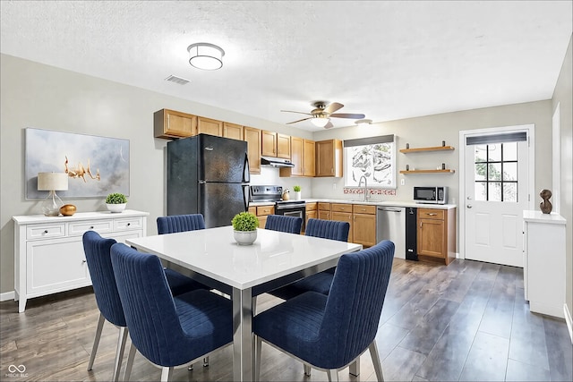 dining room featuring a textured ceiling, dark wood finished floors, visible vents, and a ceiling fan