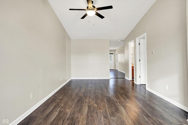 empty room featuring lofted ceiling, dark wood-style flooring, a ceiling fan, and baseboards