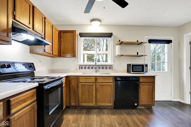 kitchen featuring black appliances, a sink, light countertops, and under cabinet range hood