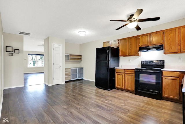 kitchen featuring black appliances, under cabinet range hood, visible vents, and brown cabinetry