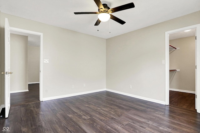 unfurnished bedroom with baseboards, ceiling fan, wood finished floors, a spacious closet, and a closet