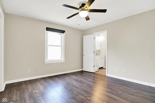 unfurnished bedroom featuring a ceiling fan, baseboards, dark wood-type flooring, and ensuite bathroom