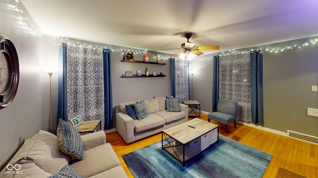 living room with visible vents, ceiling fan, baseboards, and wood finished floors