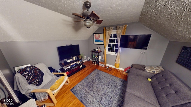 living room featuring ceiling fan, vaulted ceiling, a textured ceiling, and wood finished floors