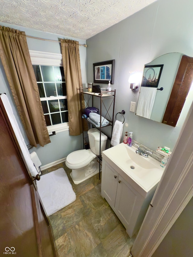 half bathroom featuring toilet, a textured ceiling, and vanity