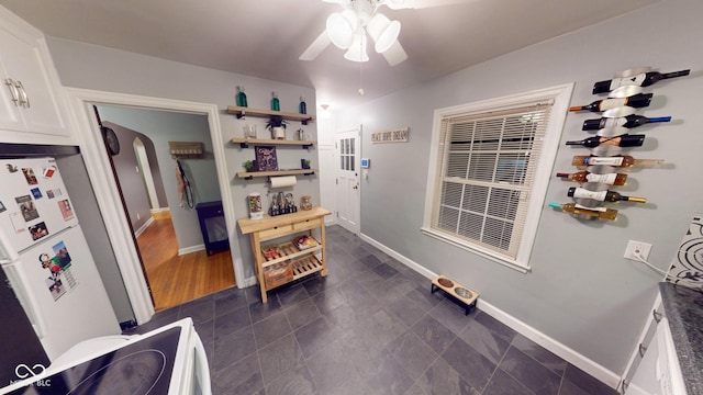 interior space with arched walkways, a ceiling fan, and baseboards