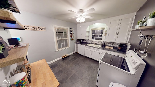 kitchen with stove, a sink, white cabinets, decorative backsplash, and open shelves