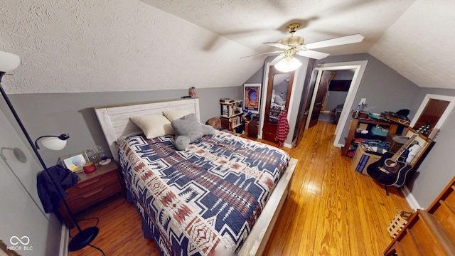 bedroom featuring baseboards, a ceiling fan, lofted ceiling, a textured ceiling, and light wood-type flooring