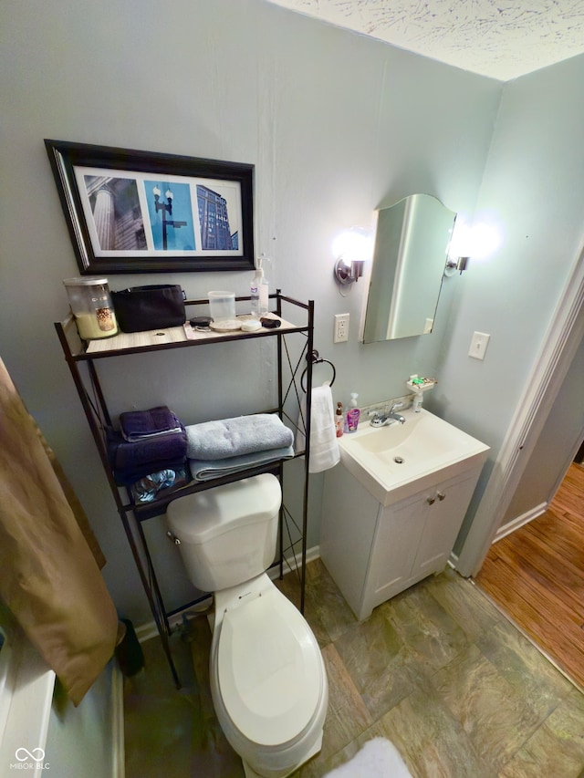 half bathroom with vanity, toilet, and a textured ceiling