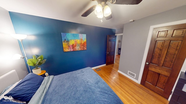 bedroom featuring a ceiling fan, baseboards, visible vents, and wood finished floors