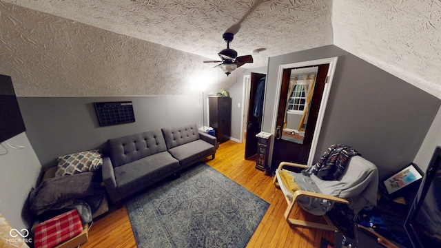 living area with a textured ceiling, vaulted ceiling, and wood finished floors