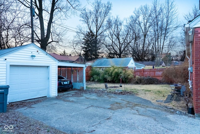 detached garage featuring aphalt driveway and fence