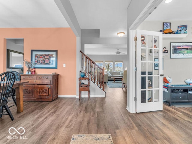 interior space featuring a ceiling fan, baseboards, stairway, and wood finished floors