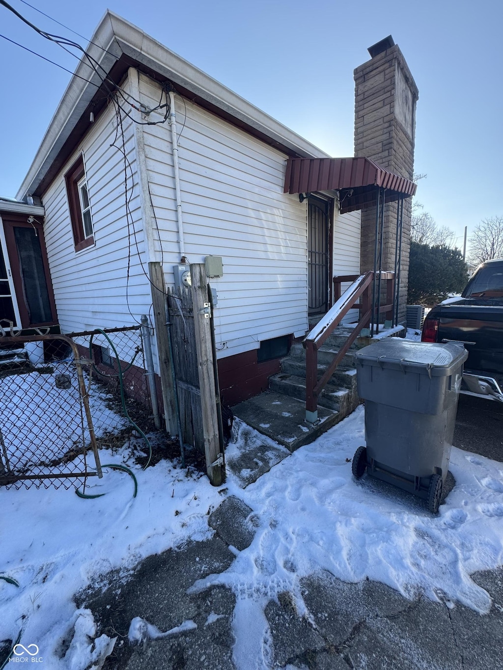 view of snowy exterior featuring a chimney and fence