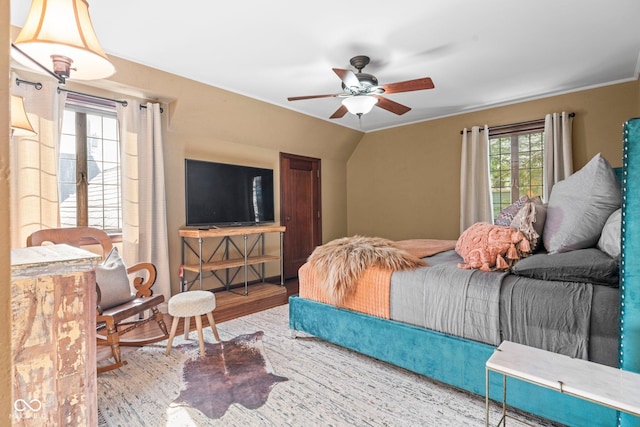 bedroom featuring multiple windows, lofted ceiling, wood finished floors, and a ceiling fan