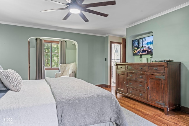 bedroom with a ceiling fan, crown molding, baseboards, and wood finished floors