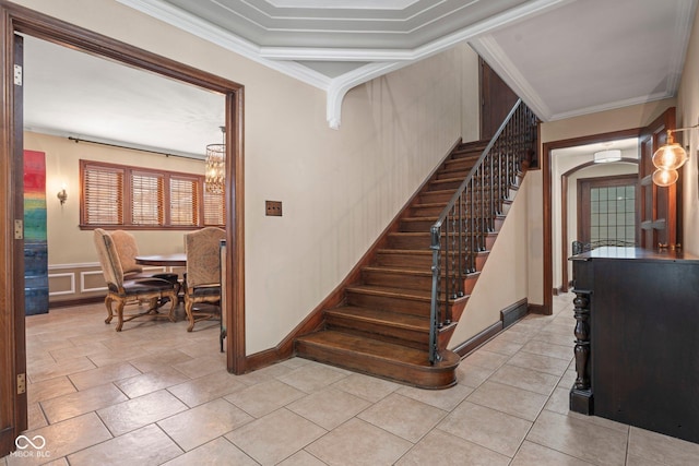 staircase featuring ornamental molding, a decorative wall, an inviting chandelier, wainscoting, and tile patterned flooring