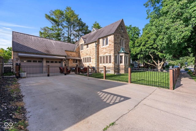 view of front of home featuring a front lawn, an attached garage, stone siding, and driveway