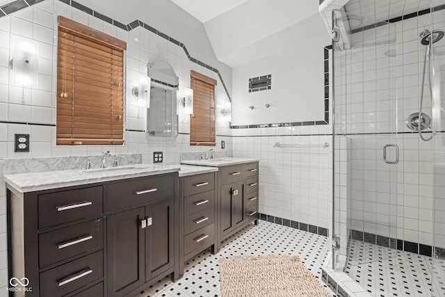 bathroom featuring vanity, lofted ceiling, a stall shower, tile patterned floors, and tile walls