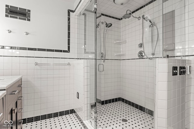 bathroom featuring visible vents, a shower stall, vanity, and tile walls