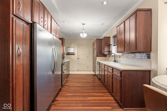 kitchen with ornamental molding, a sink, dark wood-style floors, appliances with stainless steel finishes, and light countertops