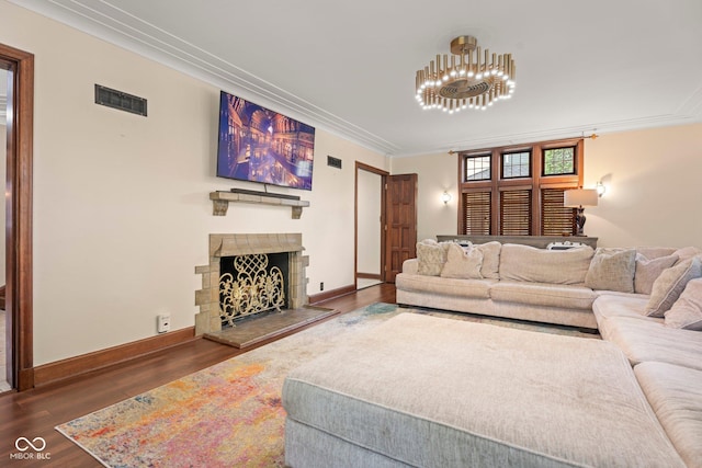 living room featuring visible vents, a fireplace with raised hearth, wood finished floors, crown molding, and baseboards