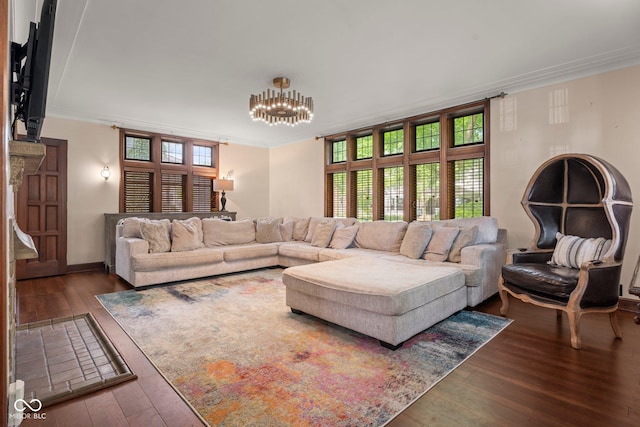 living room with crown molding, hardwood / wood-style flooring, a notable chandelier, and baseboards