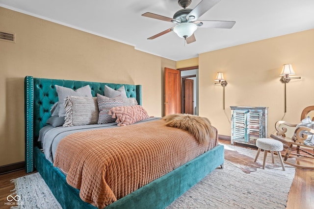 bedroom with visible vents, a ceiling fan, wood finished floors, crown molding, and baseboards