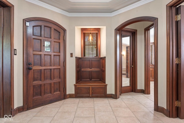 foyer with arched walkways, crown molding, baseboards, and light tile patterned flooring