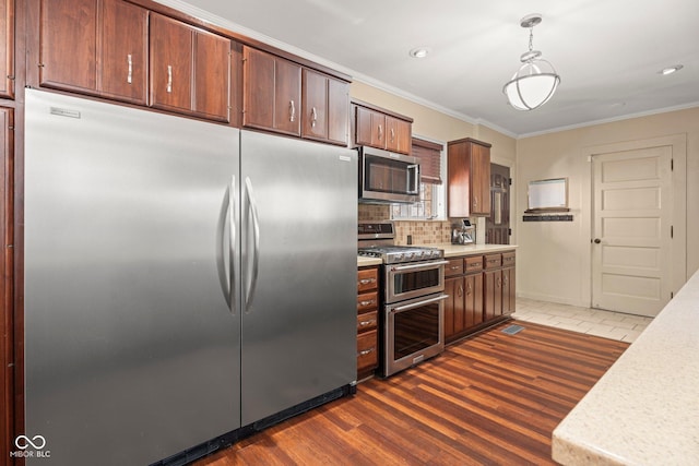 kitchen featuring stainless steel appliances, light countertops, dark wood-type flooring, and ornamental molding