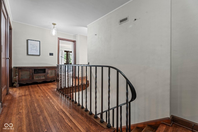 staircase featuring wood finished floors, visible vents, and ornamental molding