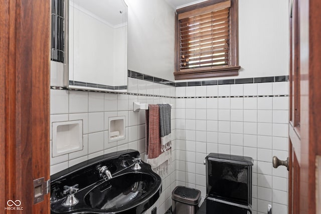 bathroom featuring tile walls, crown molding, and a sink