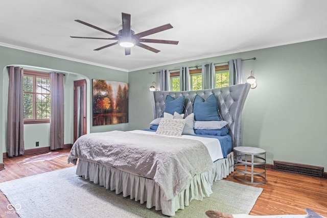 bedroom with visible vents, multiple windows, crown molding, and wood finished floors