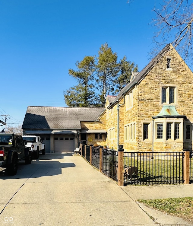 view of front facade featuring concrete driveway, an attached garage, fence, and stone siding