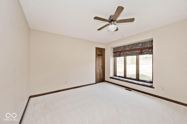 carpeted empty room featuring a ceiling fan, visible vents, and baseboards