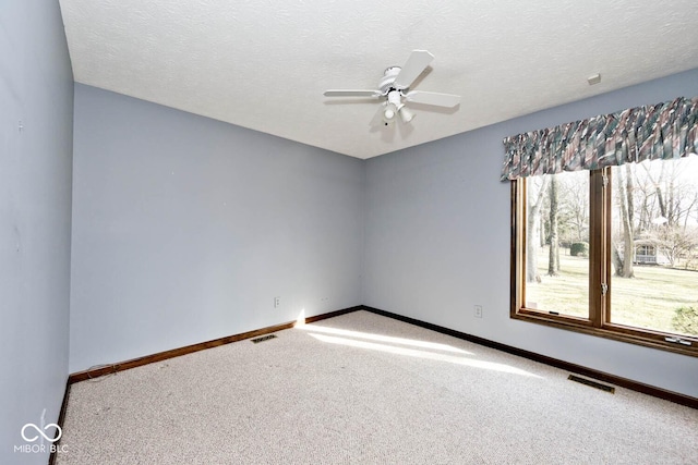 empty room featuring ceiling fan, carpet flooring, visible vents, and baseboards