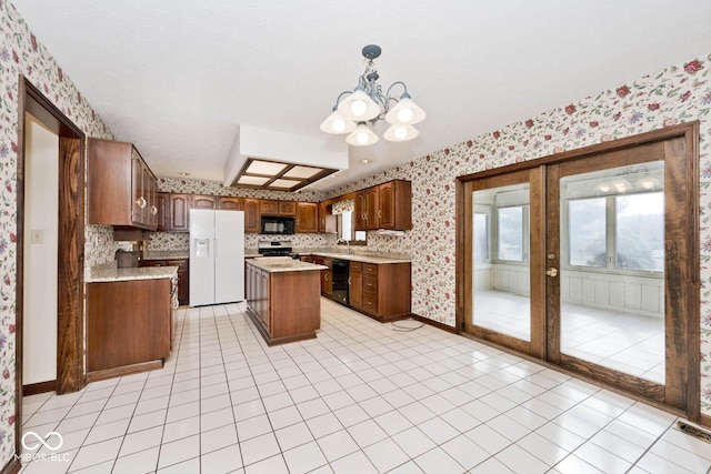 kitchen featuring a sink, a kitchen island, light countertops, black appliances, and wallpapered walls