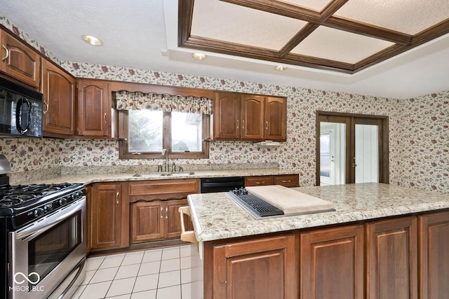 kitchen with light tile patterned flooring, a sink, light stone countertops, black appliances, and wallpapered walls