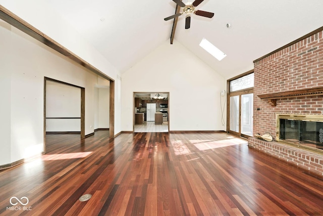 unfurnished living room featuring high vaulted ceiling, a skylight, wood finished floors, a brick fireplace, and beam ceiling